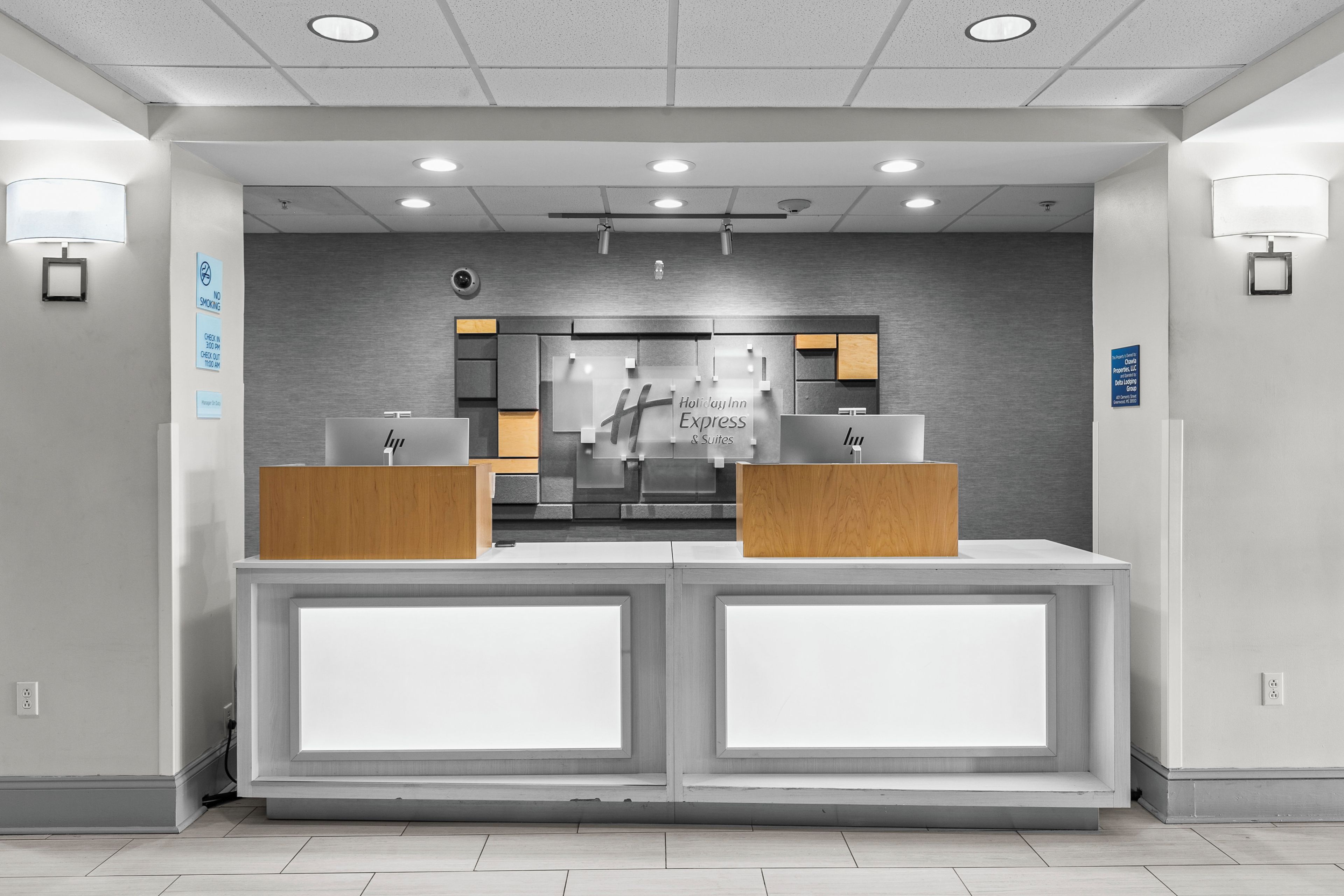A hotel reception desk with a modern design, featuring a check-in counter, a digital display, and a wall-mounted sign indicating hotel services.