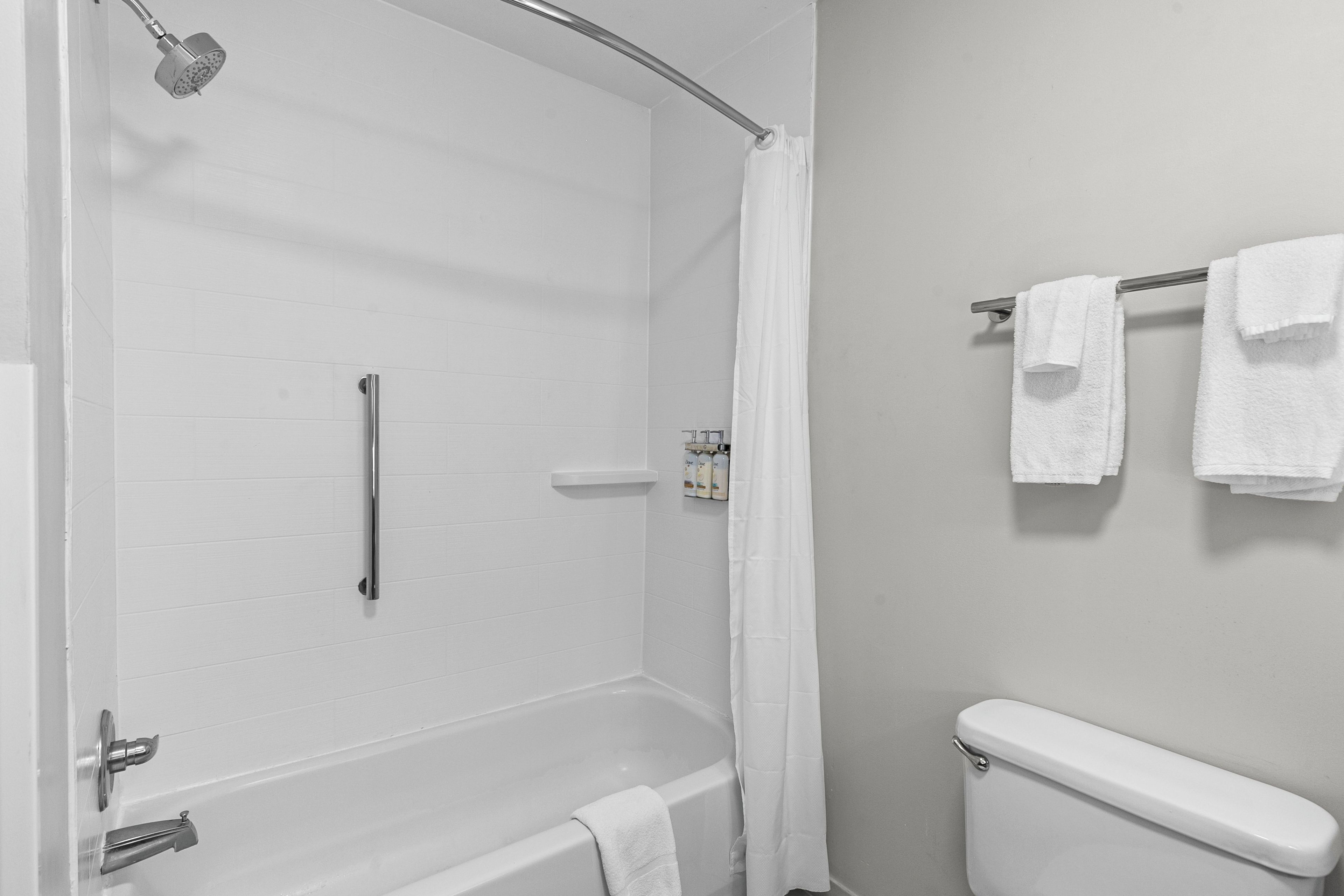 A bathroom with a bathtub, toilet, shower, and towel rack.