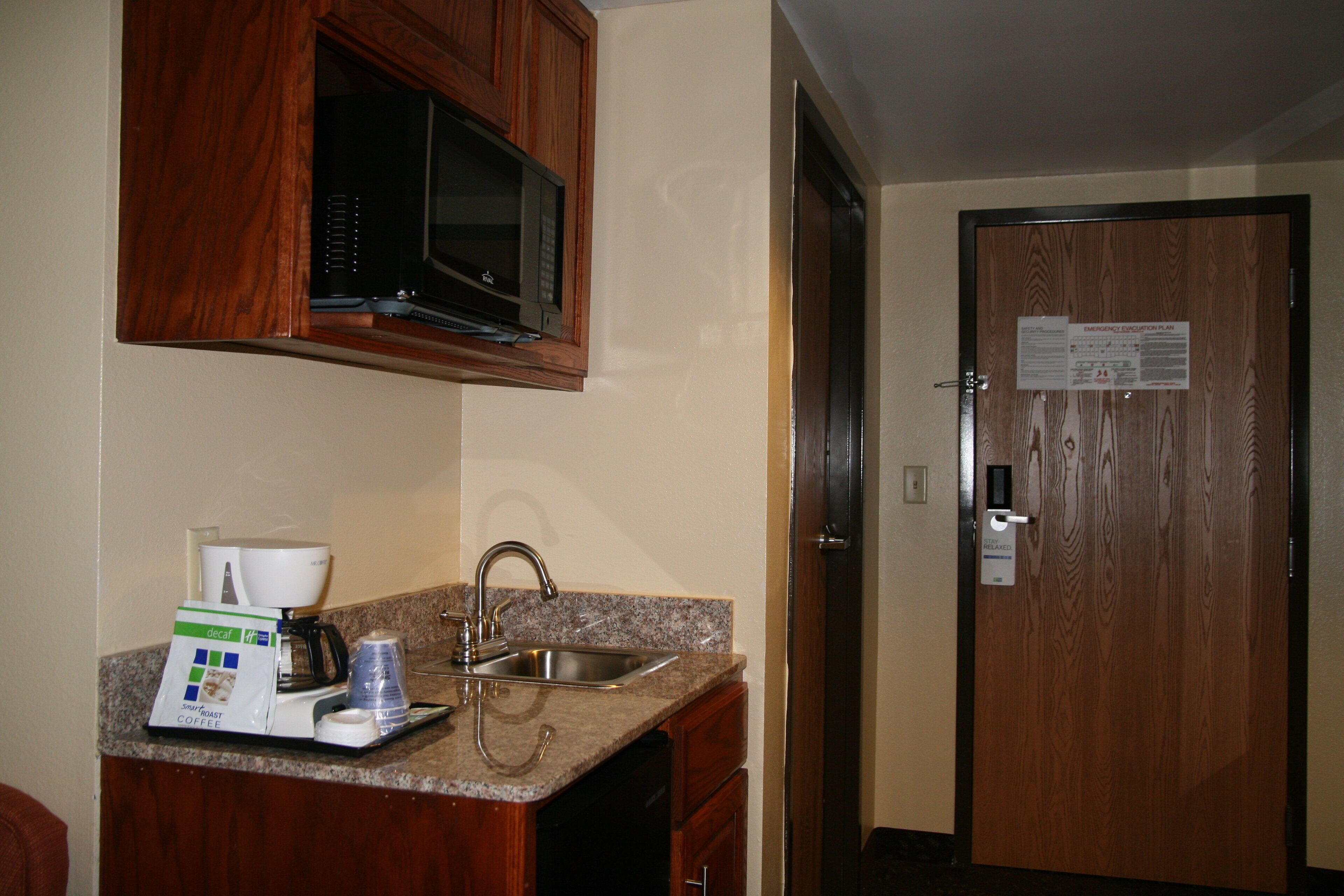 Una cocina equipada con microondas, cafetera y lavabo.