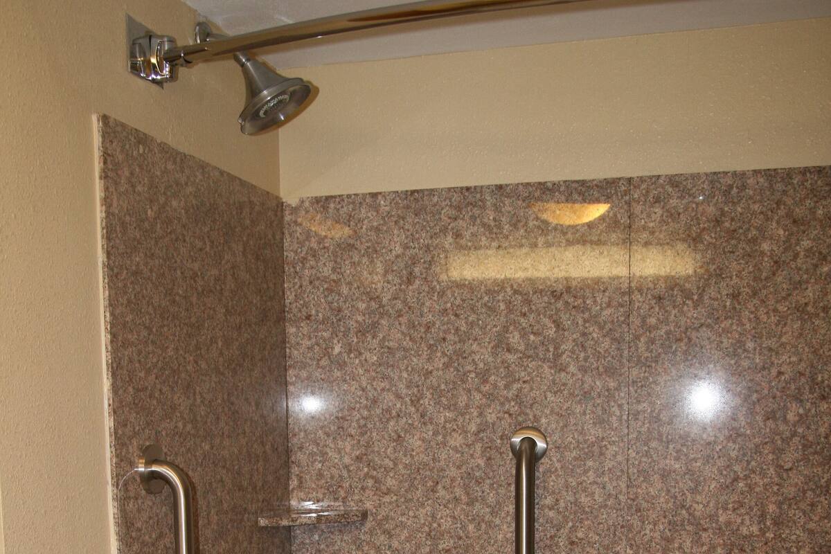 A bathroom with a bathtub, grab bars, and a showerhead.