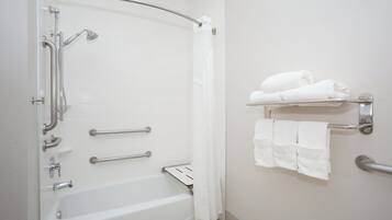 A bathroom with a walk-in shower, grab bars, a towel rack, and a toilet.