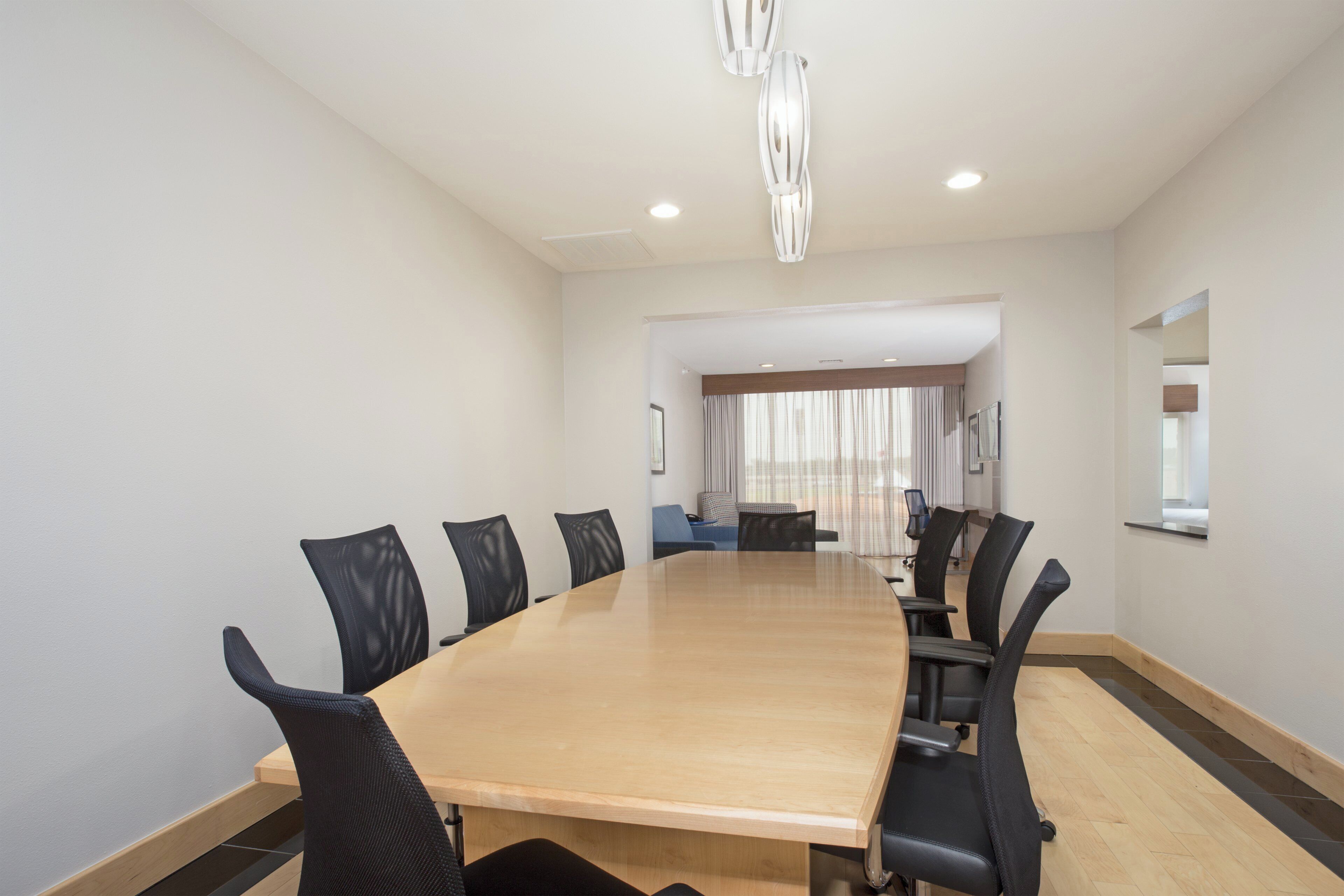 A conference room with a long table, black chairs, and a modern chandelier.