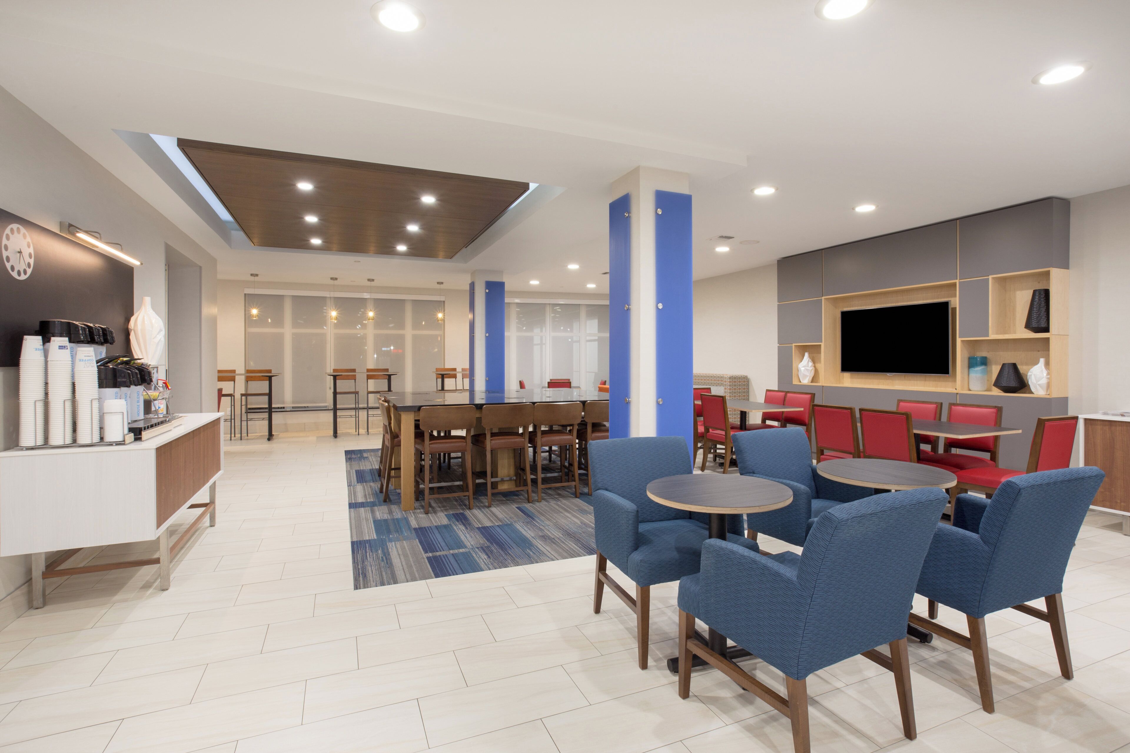 Un hall d’hôtel moderne avec un comptoir d’accueil, un espace salon et un grand écran de télévision.