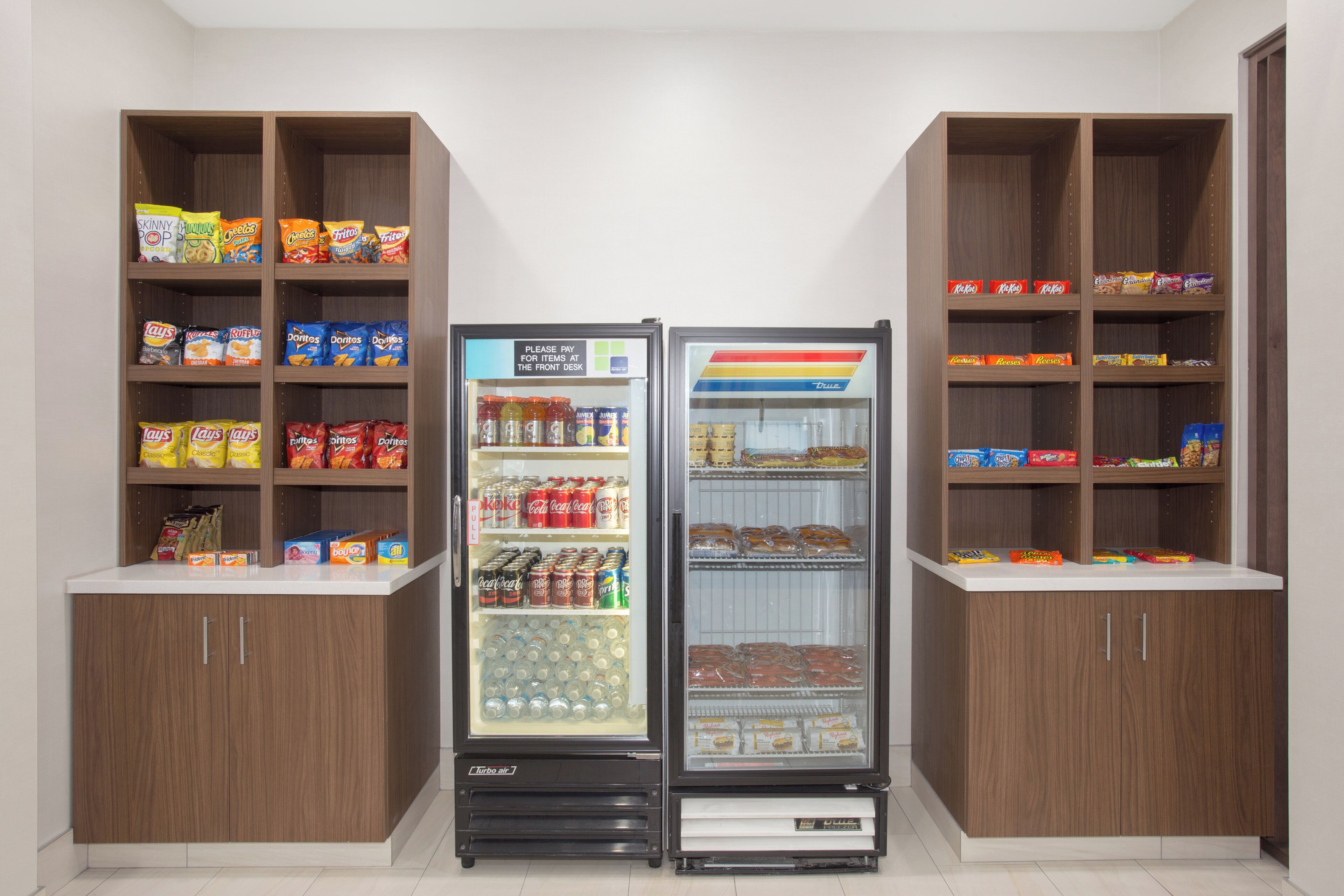 A vending machine with snacks and drinks, surrounded by wooden cabinets with various packaged goods.