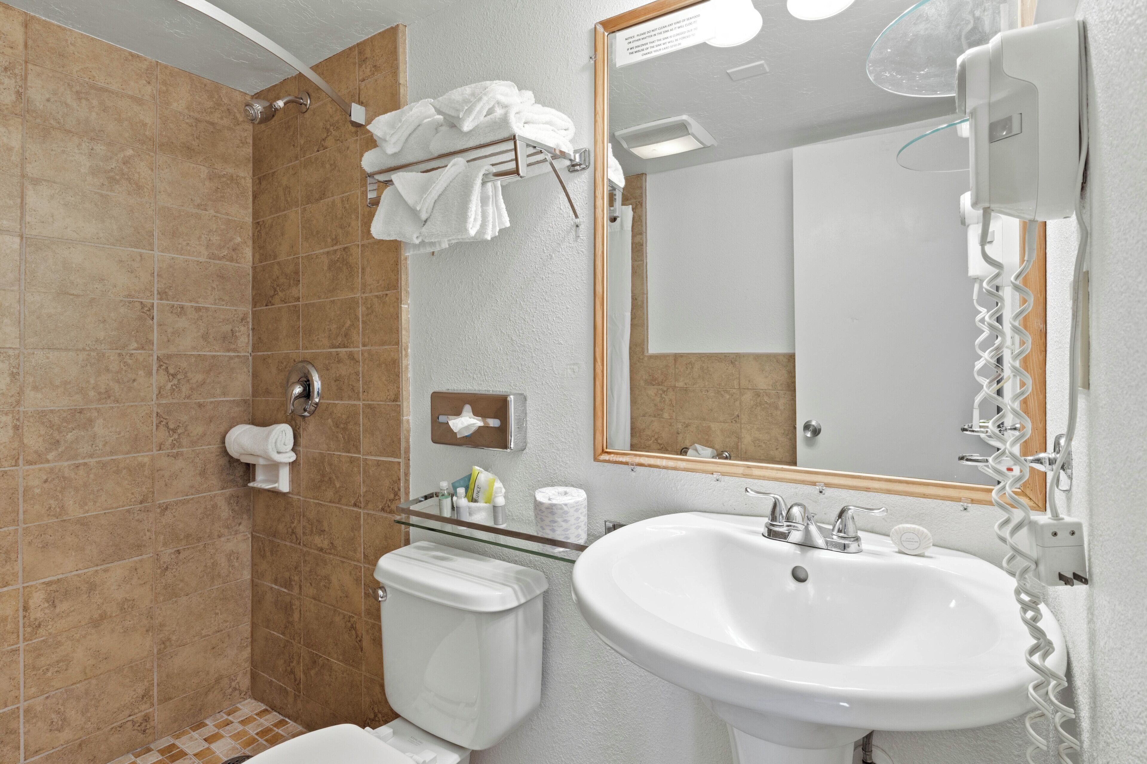 Ein Badezimmer mit Dusche, Toilette, Waschbecken und Spiegel.