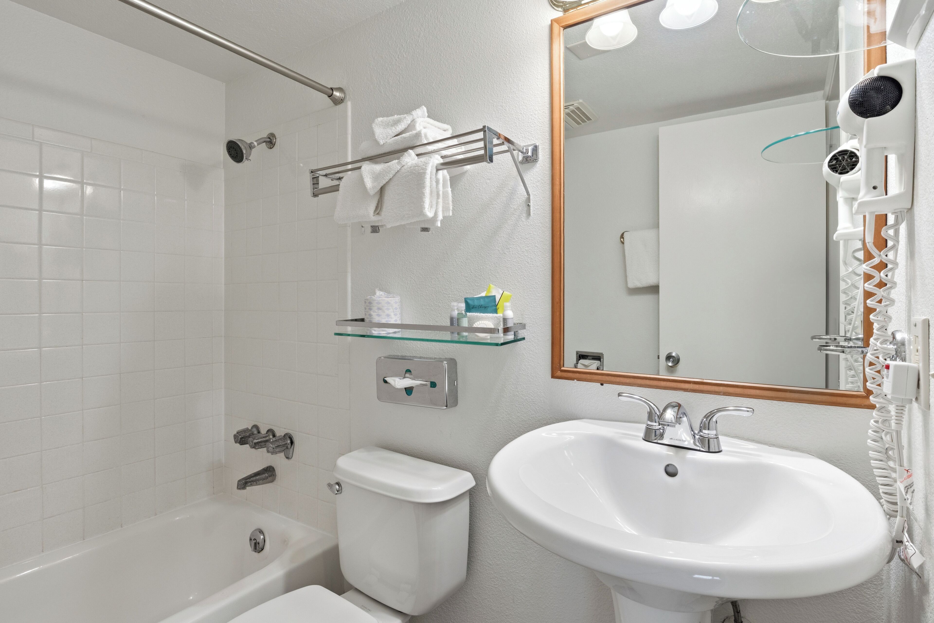 A bathroom with a bathtub, toilet, sink, and a mirror.