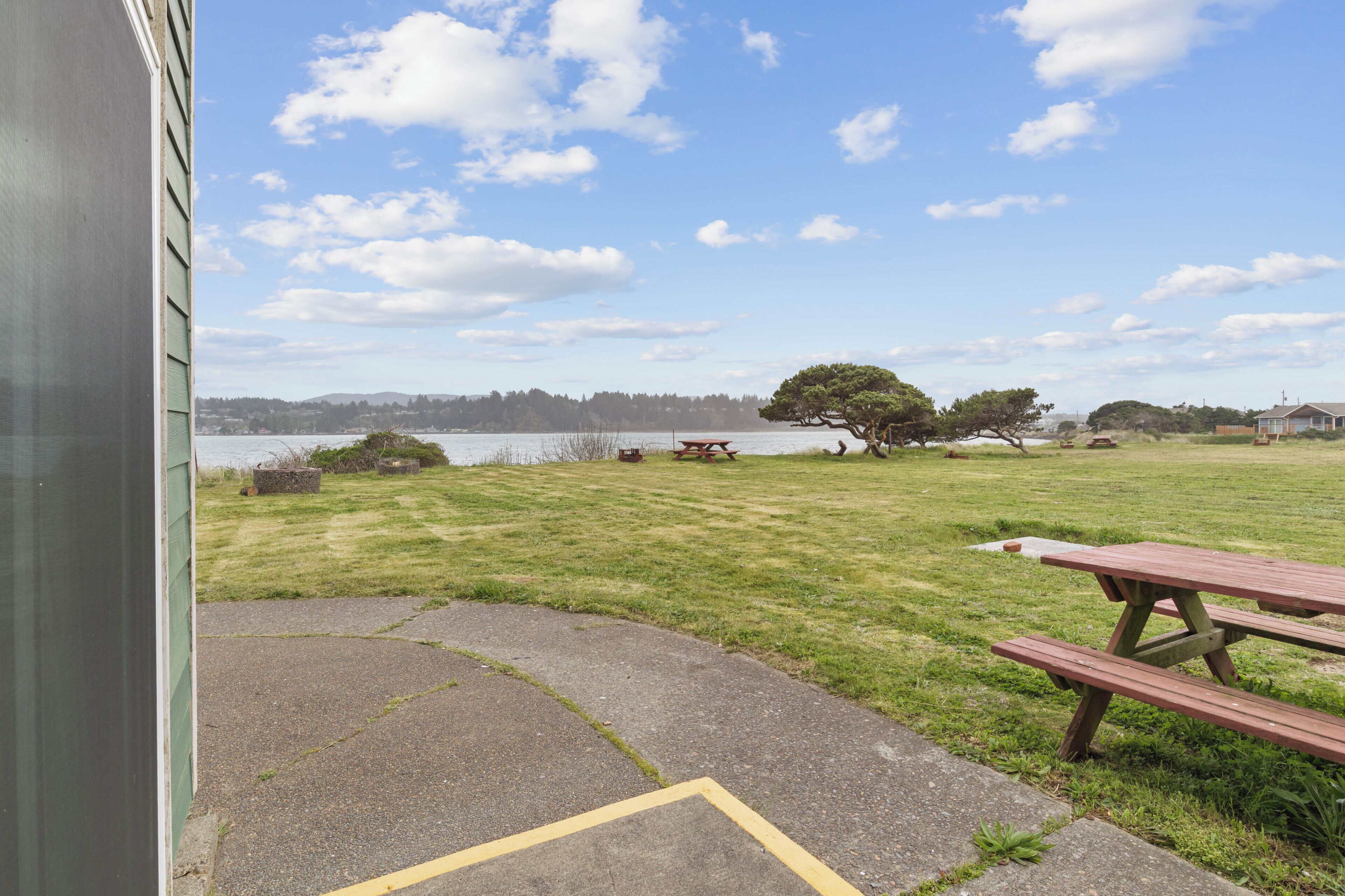 Een gazon met picknicktafels en uitzicht op een meer.