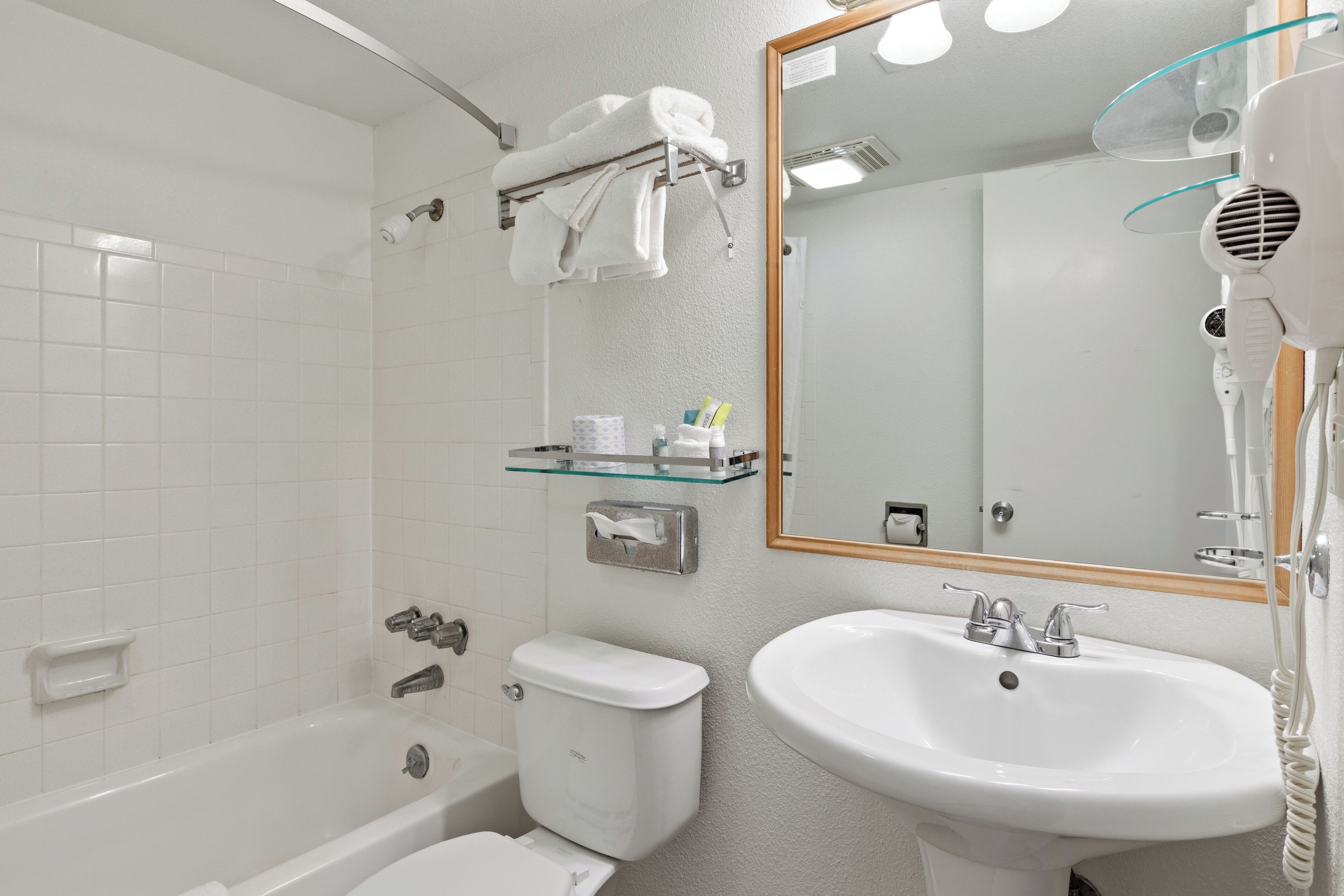 A bathroom with a bathtub, toilet, sink, and a hairdryer.