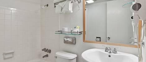 A bathroom with a bathtub, toilet, sink, and a hairdryer.