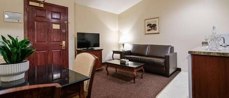 A living room with a sofa, TV, coffee table, and a dining area with a table and chairs.