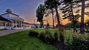 A white building with a balcony, surrounded by a well-maintained lawn and flowering plants. - Four Seasons Island Resort (Pembine)