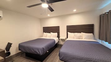 Une chambre d’hôtel avec deux lits, un ventilateur de plafond et un bureau avec une chaise.