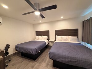 A hotel room with two beds, a ceiling fan, and a desk with a chair. -  SurfSide Stay Morro Bay (Morro Bay)