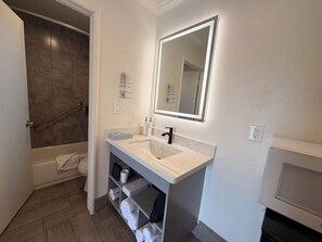 A modern bathroom with a bathtub, a sink with a mirror, and a shower area. -  SurfSide Stay Morro Bay (Morro Bay)