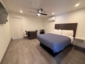 A bedroom with a bed, a desk, a chair, a ceiling fan, and an air conditioning unit. -  SurfSide Stay Morro Bay (Morro Bay)