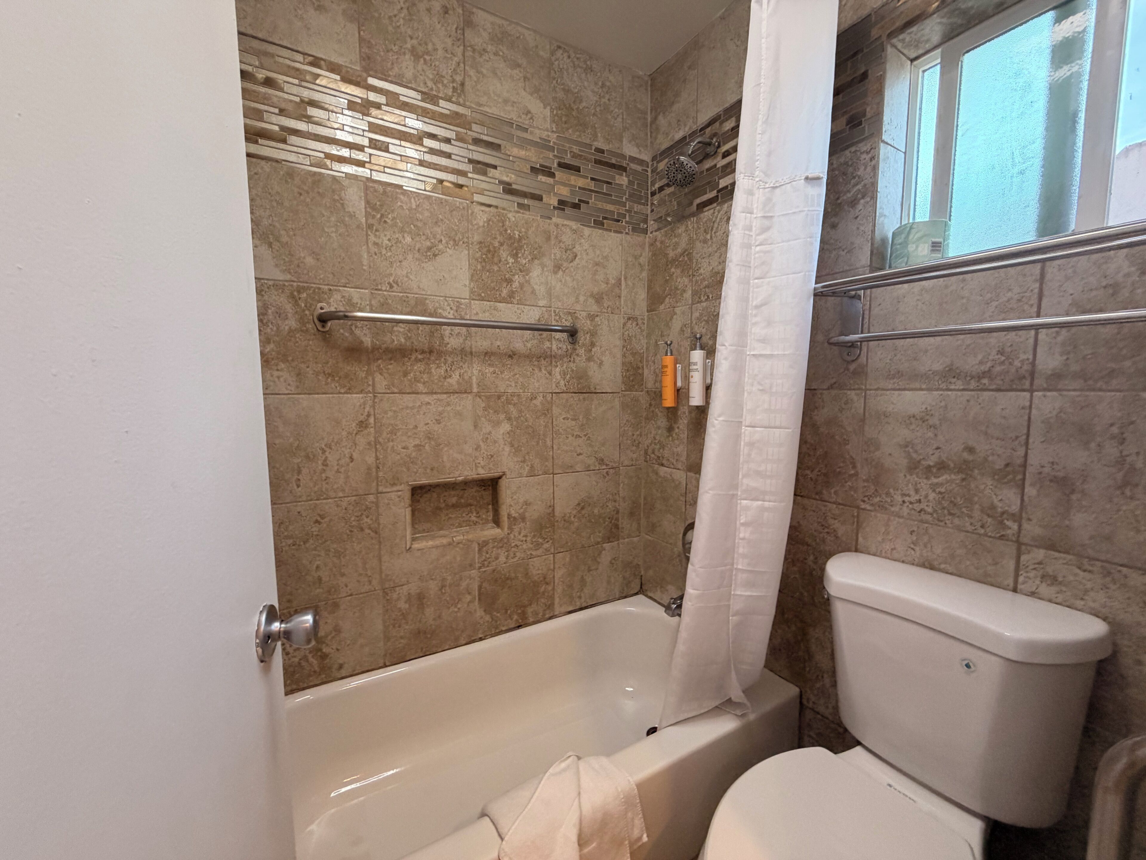 A bathroom with a bathtub, toilet, and a shower area.