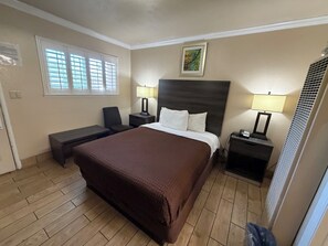 A hotel room with a large bed, two bedside tables with lamps, a chair, a desk, and a window with blinds. -  SurfSide Stay Morro Bay (Morro Bay)