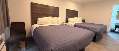 A hotel room with two beds, a ceiling fan, and a nightstand with a lamp.