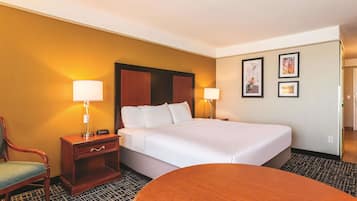 Una camera d'albergo con un letto, due comodini con lampade, una sedia e un tavolino rotondo.