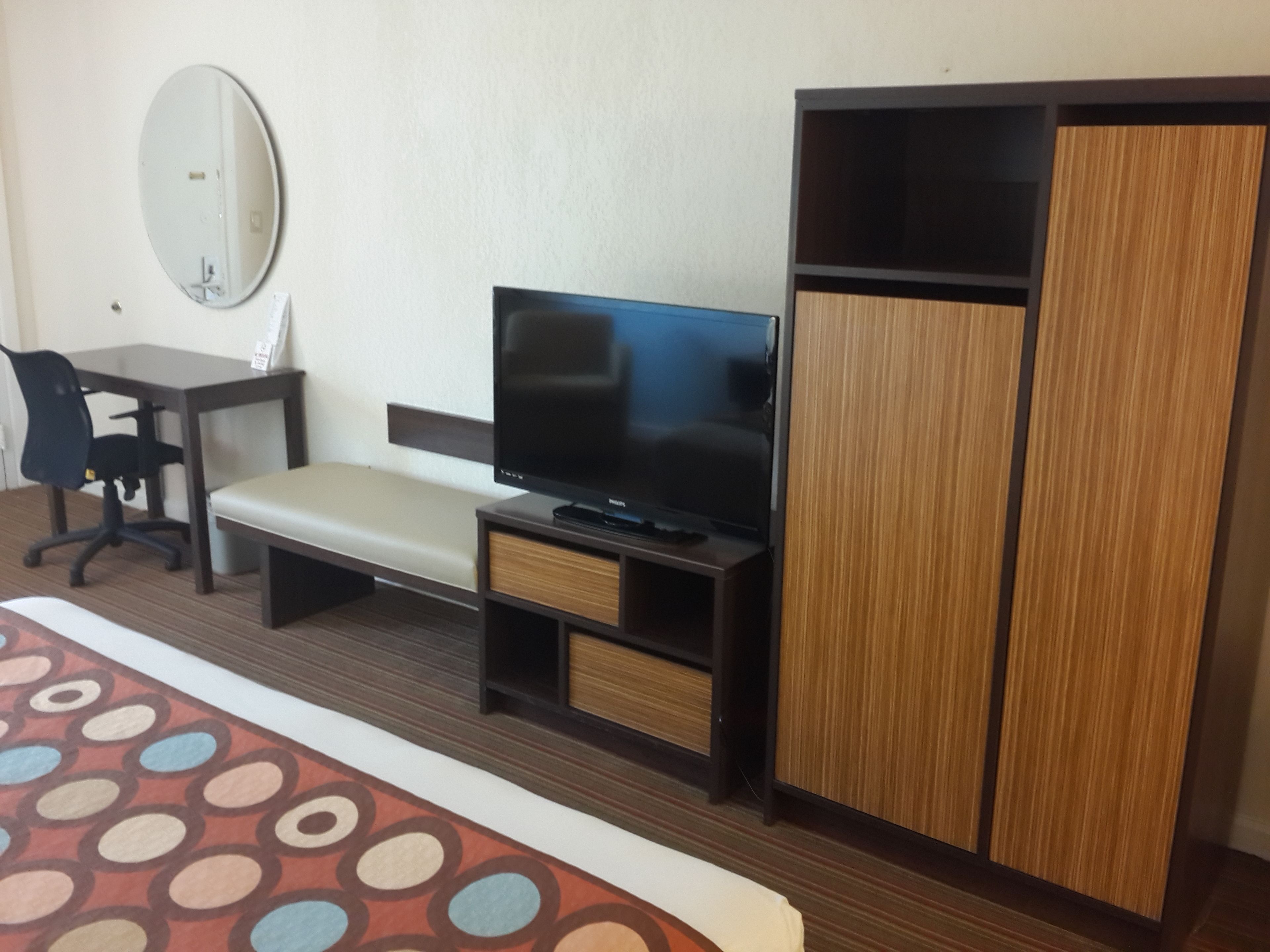 Une chambre d’hôtel comprenant un lit, un bureau, une chaise, un téléviseur et une armoire.