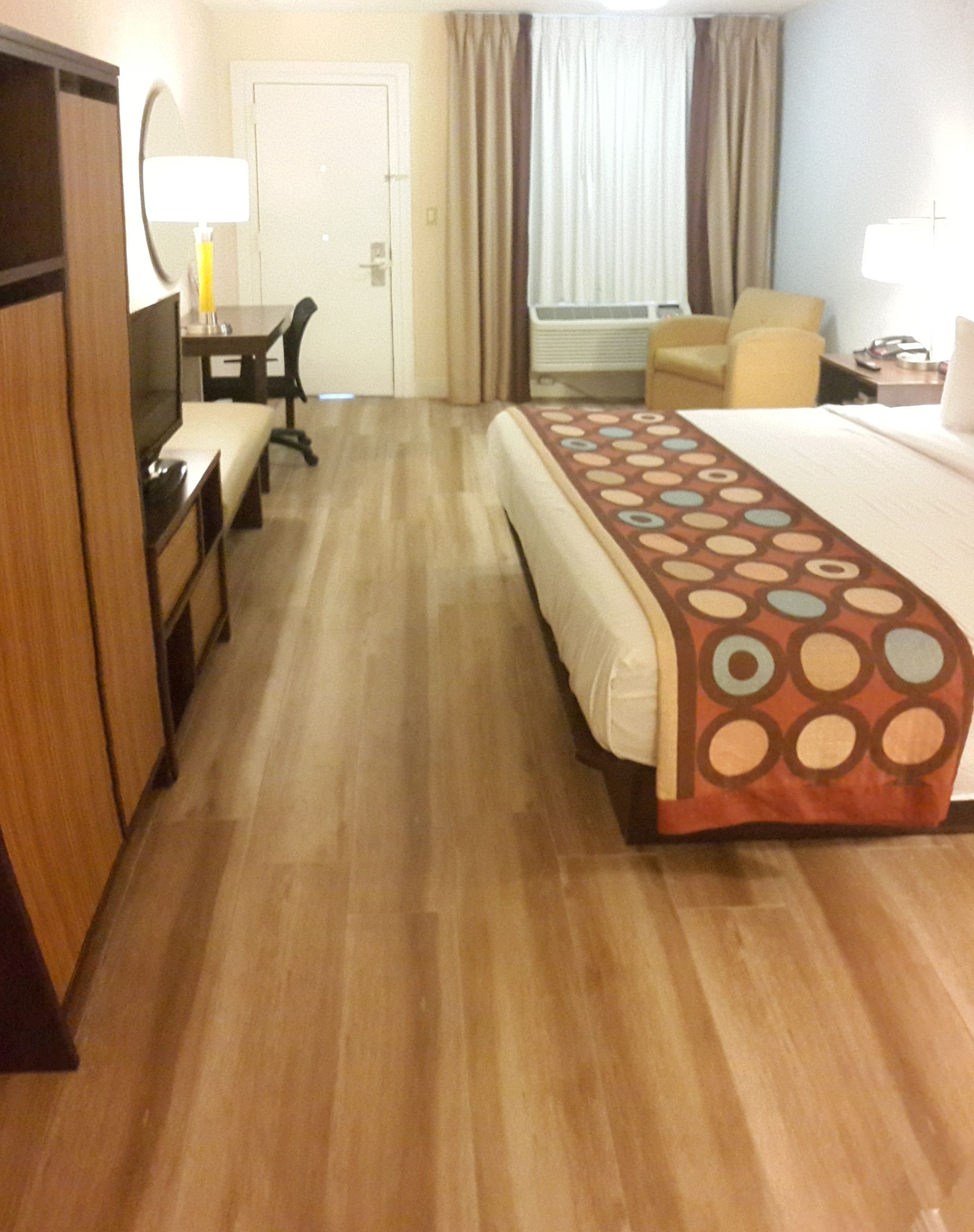Une chambre d’hôtel avec un lit, un bureau, une chaise, une armoire et une porte de salle de bain.