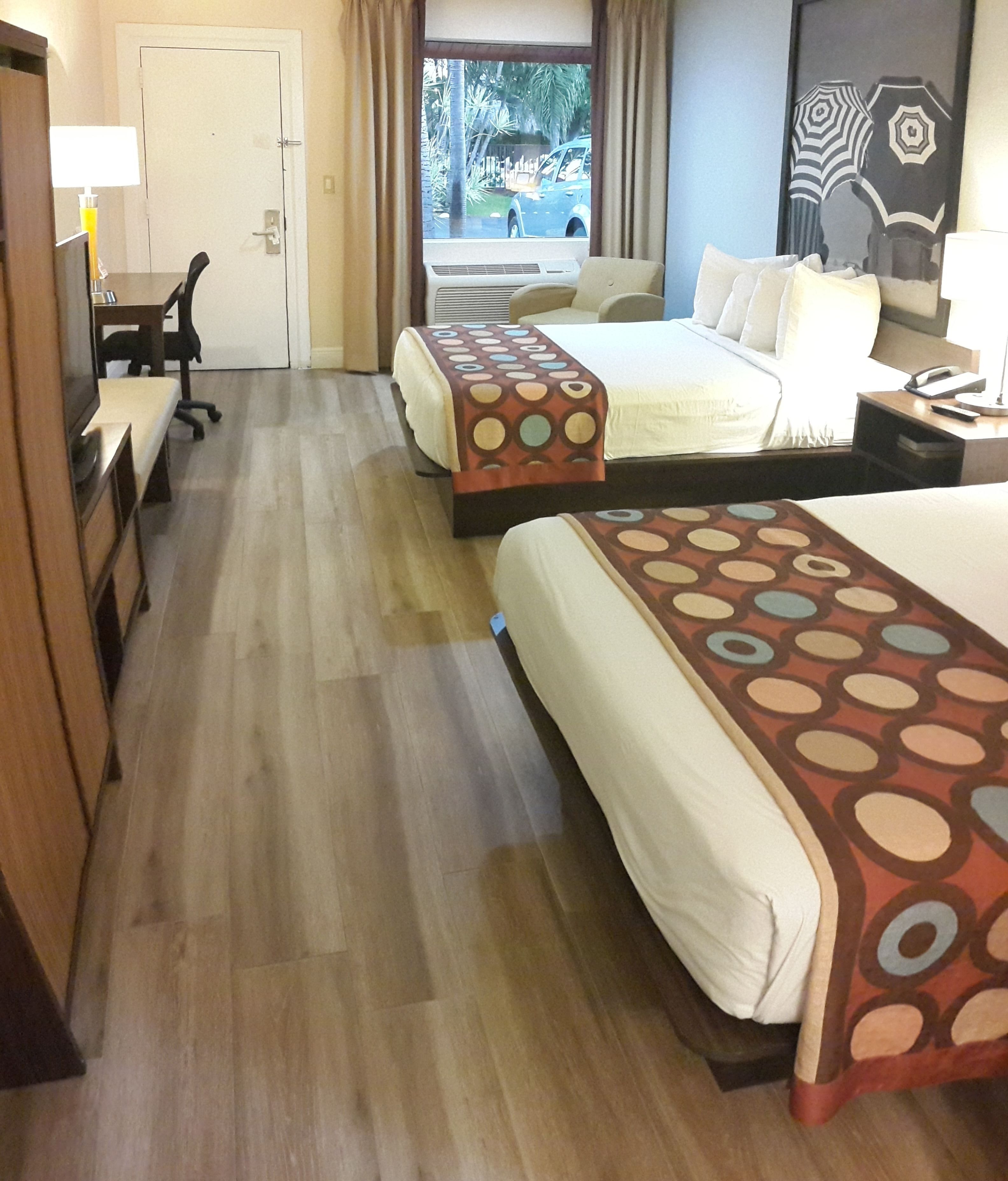 A hotel room with two beds, a desk, and a chair.