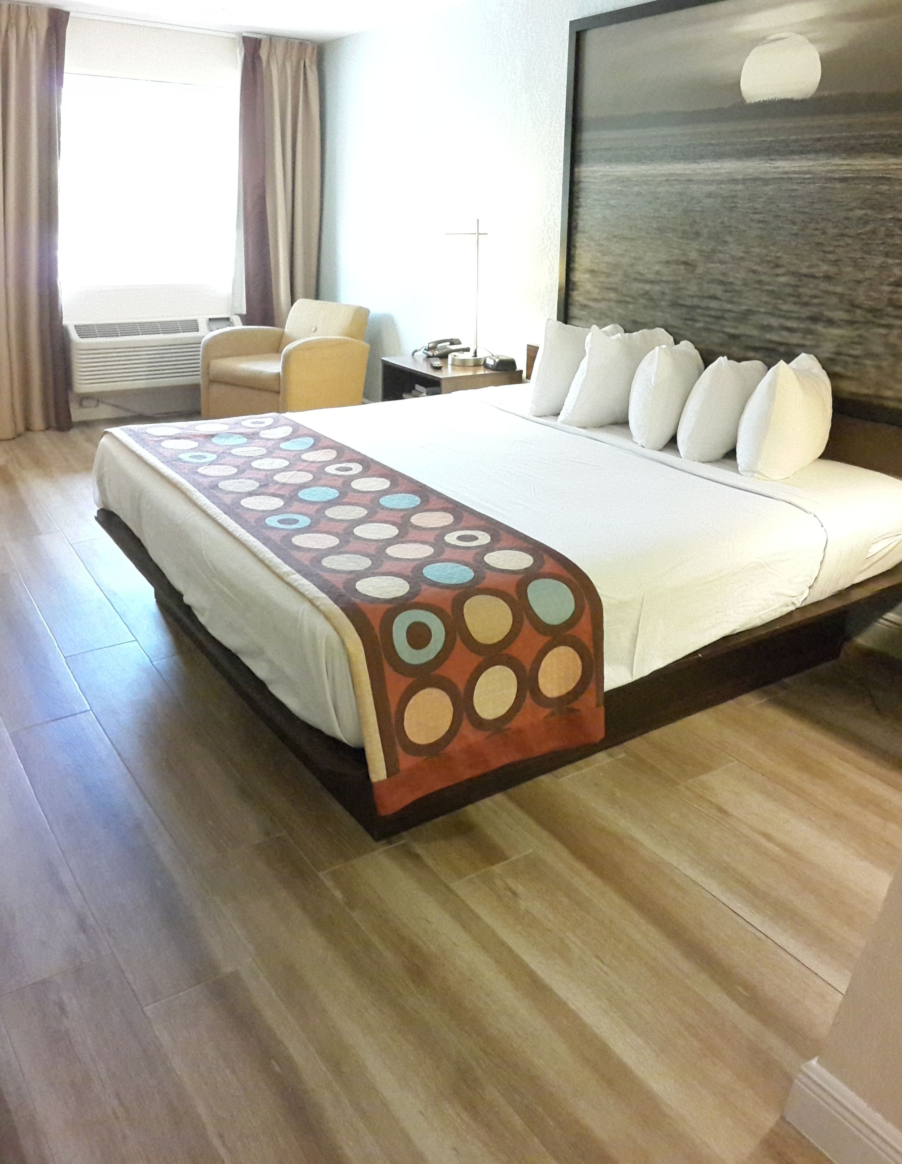 A hotel room with a large bed, a chair, a desk, and a view of the sea.
