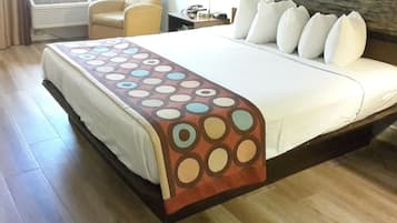 A hotel room with a large bed, a chair, a desk, and a view of the sea.