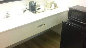 A small kitchenette with a microwave, coffee maker, and a refrigerator.