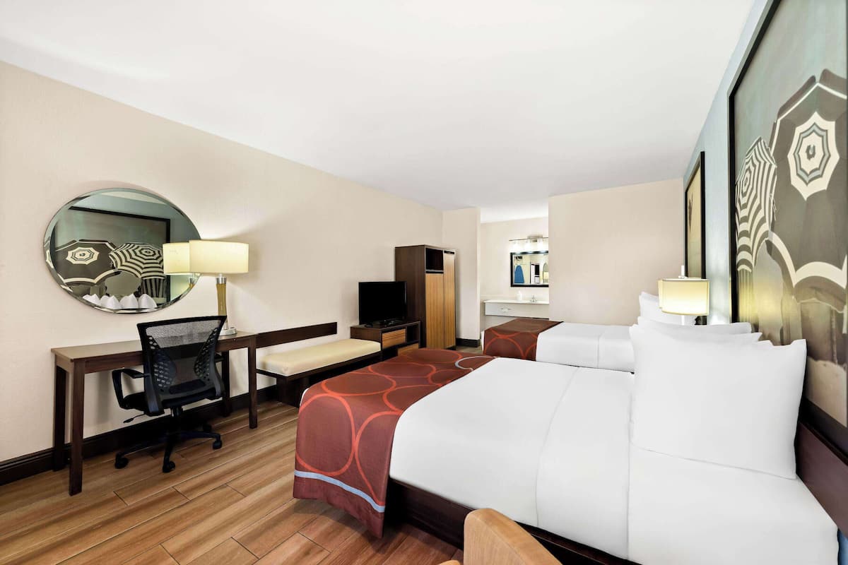A hotel room with a bed, desk, chair, and a TV.