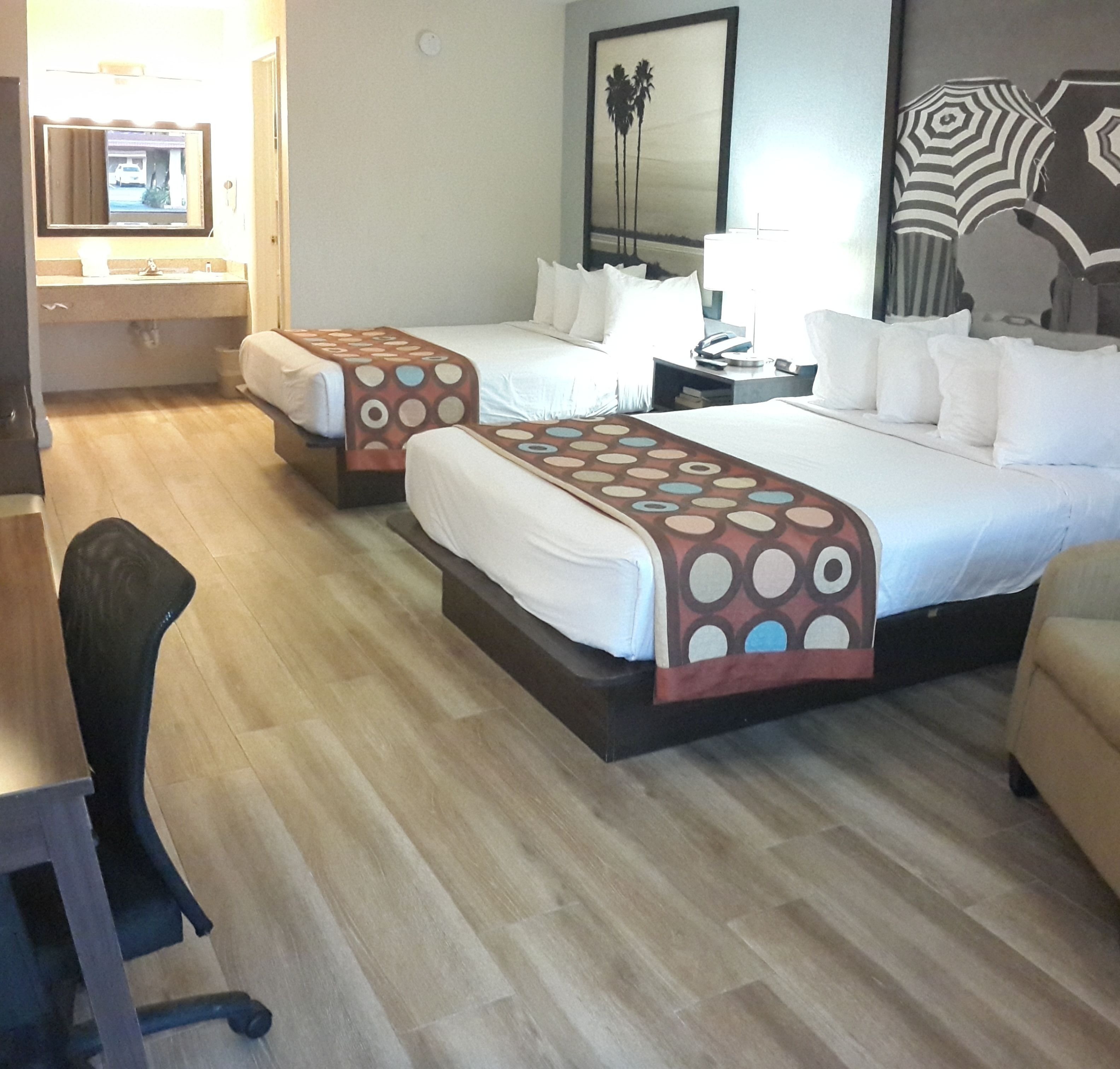 Une chambre d’hôtel avec deux lits, un bureau et une chaise.