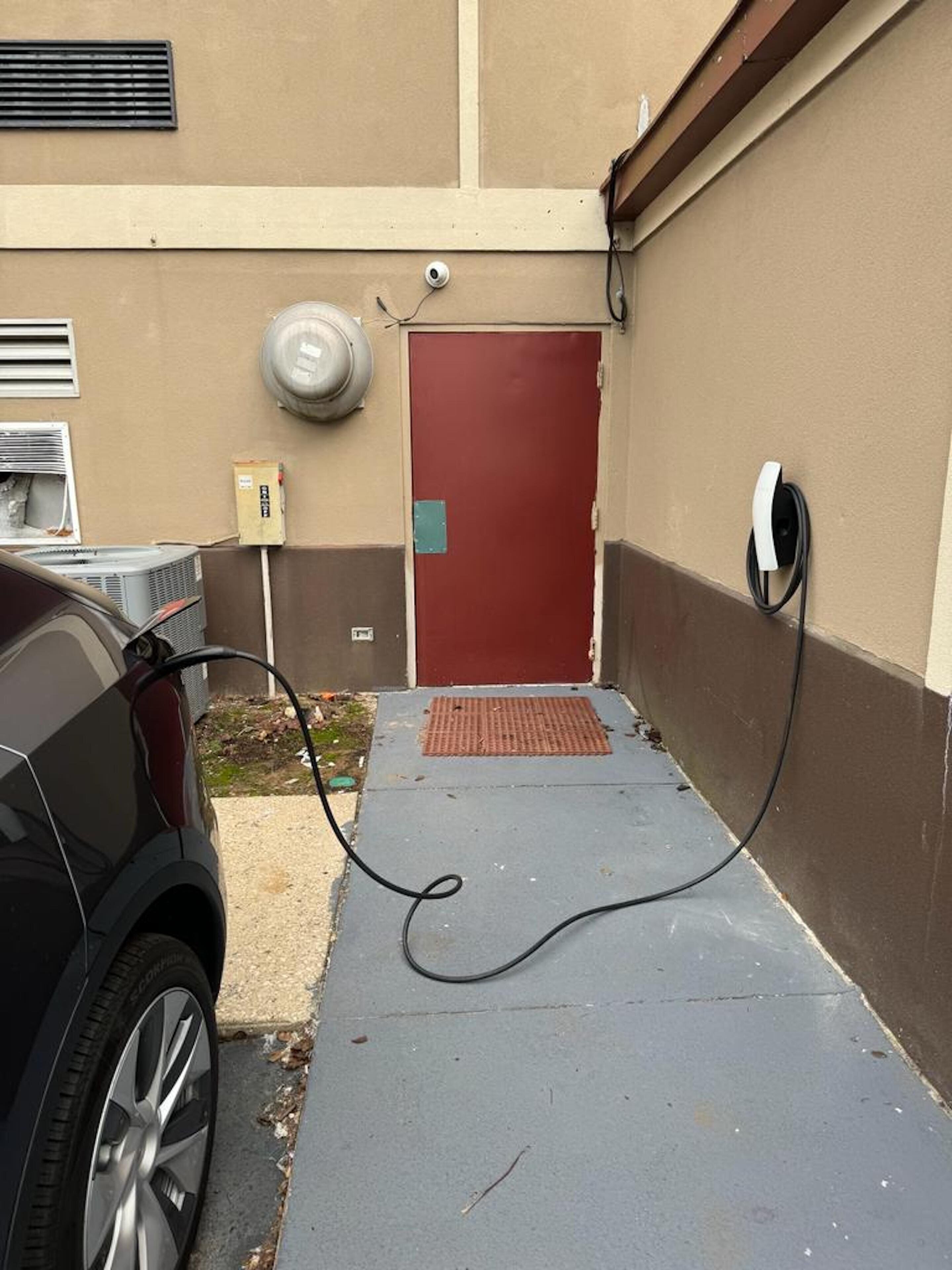 A parking area with a red door, a security camera, and a power outlet.