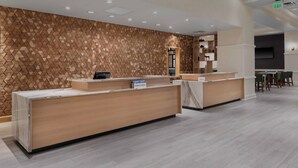 A modern reception area with wooden reception desks, a patterned wall, and a clean, tiled floor.