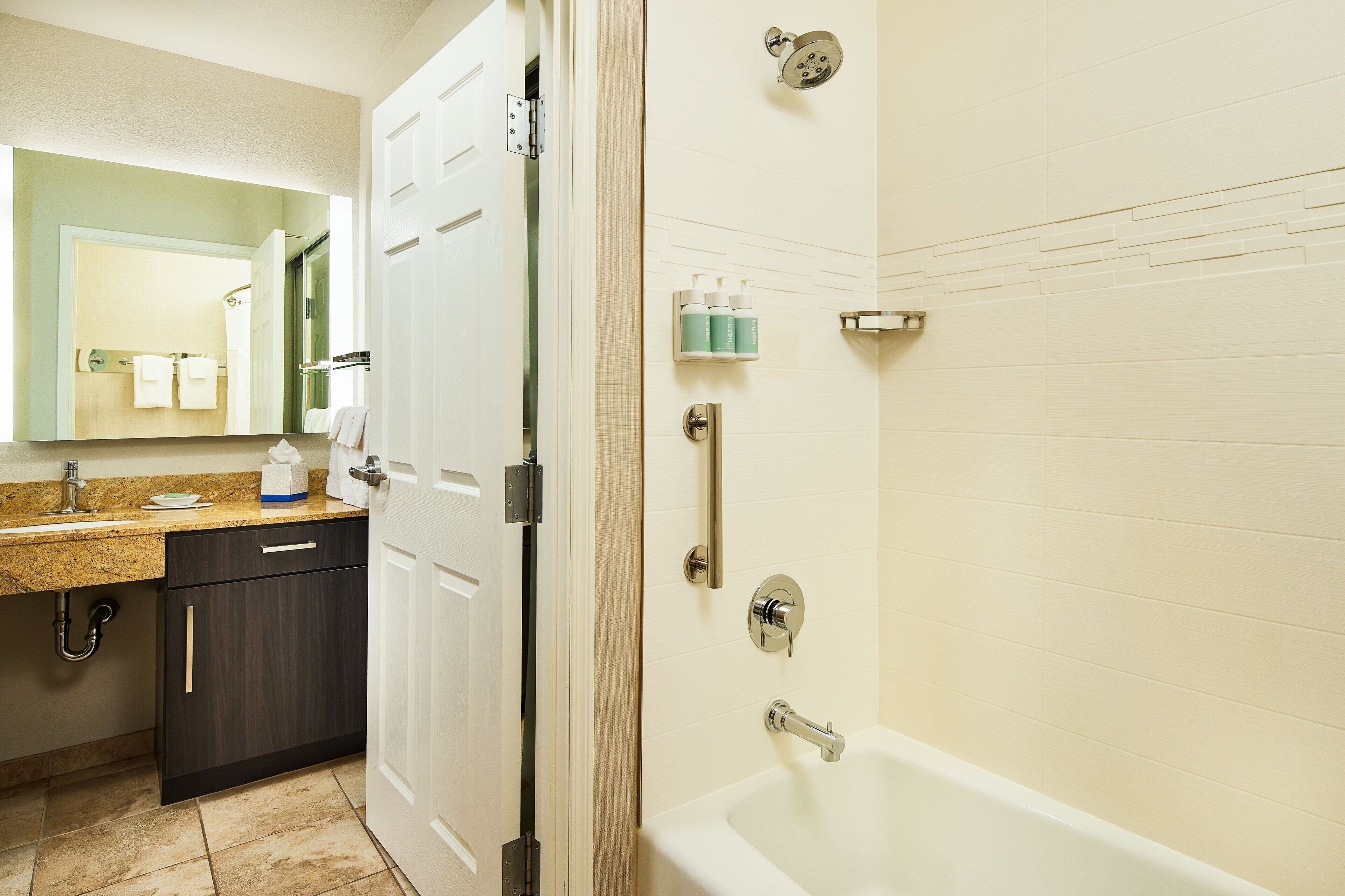 A bathroom with a sink, mirror, towel rack, and a shower area with a handheld showerhead.