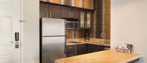 A compact kitchen with dark wood cabinets, stainless steel appliances, and a granite countertop.