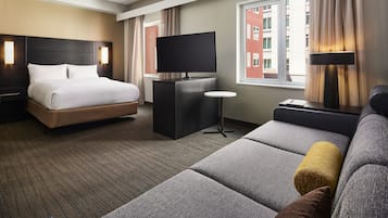 Ein Hotelzimmer mit Bett, Fernseher, Sofa und kleinem Tisch.