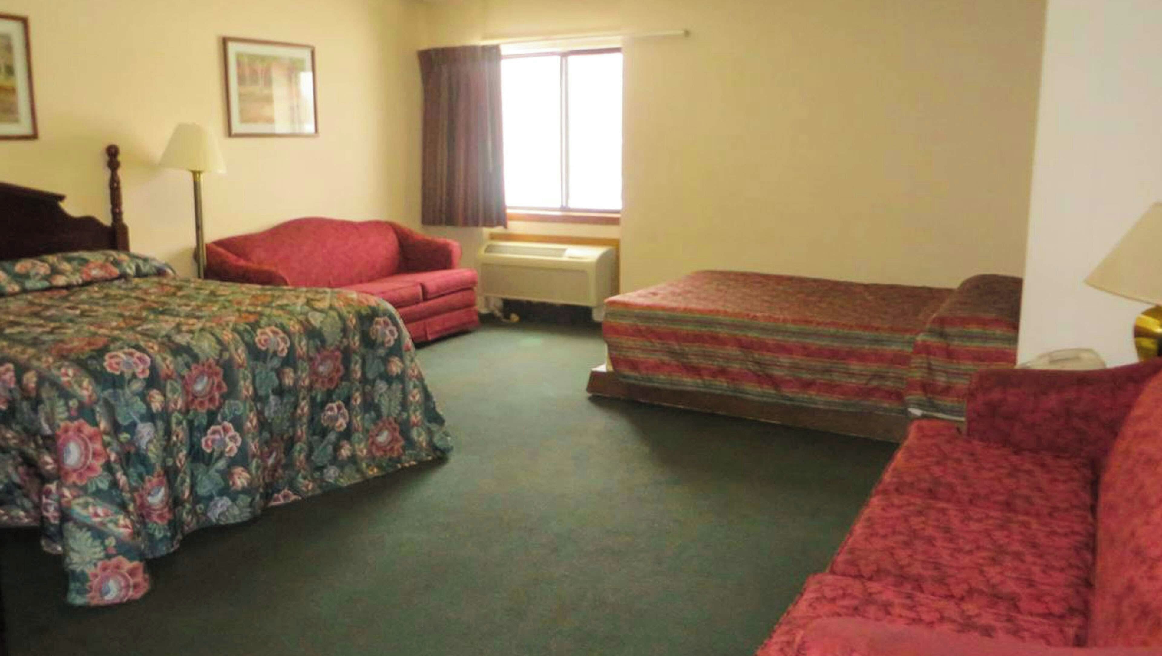 Ein Zimmer mit einem Bett, einem Sofa, einem Schreibtisch und einem Fenster.