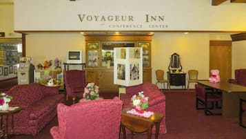 A conference room with red upholstered chairs, a wooden table, and a reception area with a clock and framed photos.