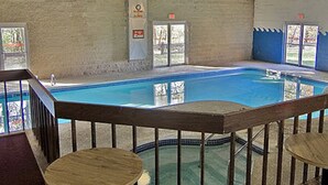 An indoor swimming pool with a wooden deck and seating area. - Voyageur Inn and Conference Center (Reedsburg)