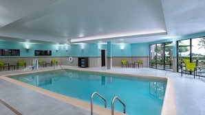 An indoor swimming pool with clear water, surrounded by green chairs and a tiled floor. - SpringHill Suites by Marriott DFW Airport East/Las Colinas (Irving)
