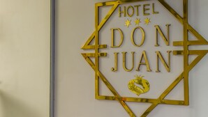 A gold geometric sign with the text "HOTEL DON JUAN" and three stars. - Hotel Don Juan (Granada)
