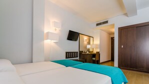 A hotel room with two beds, a desk, a chair, a television, and a wardrobe. - Hotel Don Juan (Granada)