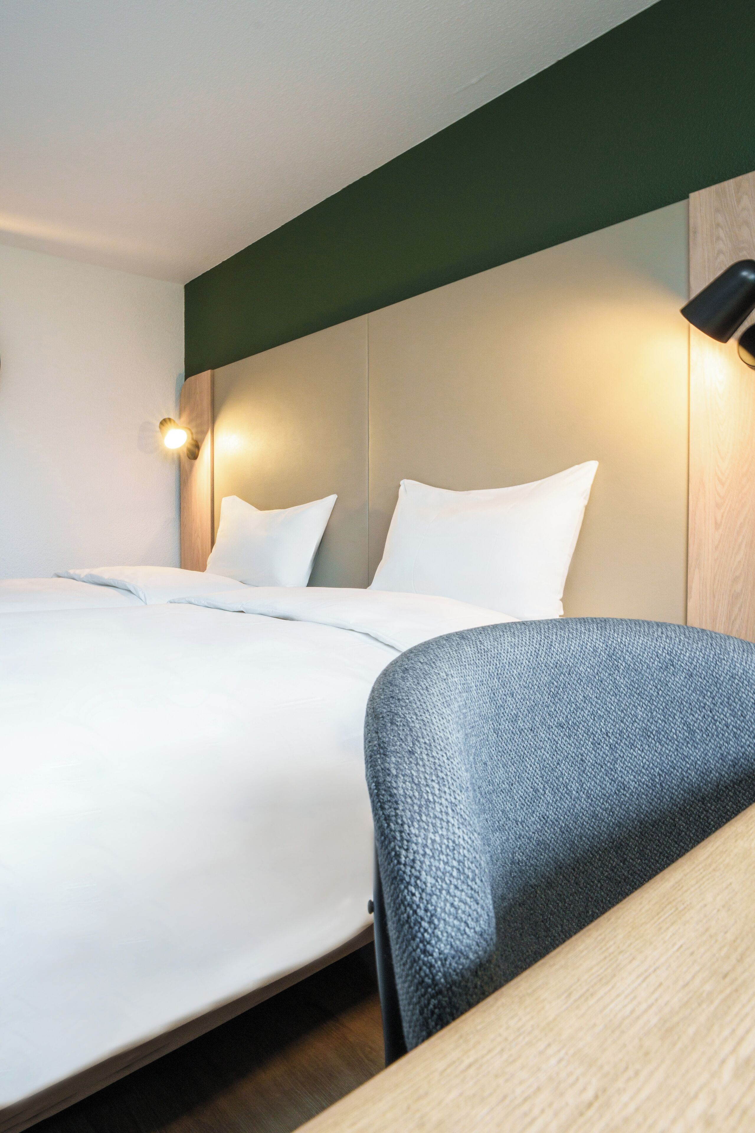 A hotel room with a bed, a nightstand, a lamp, and a wooden headboard.