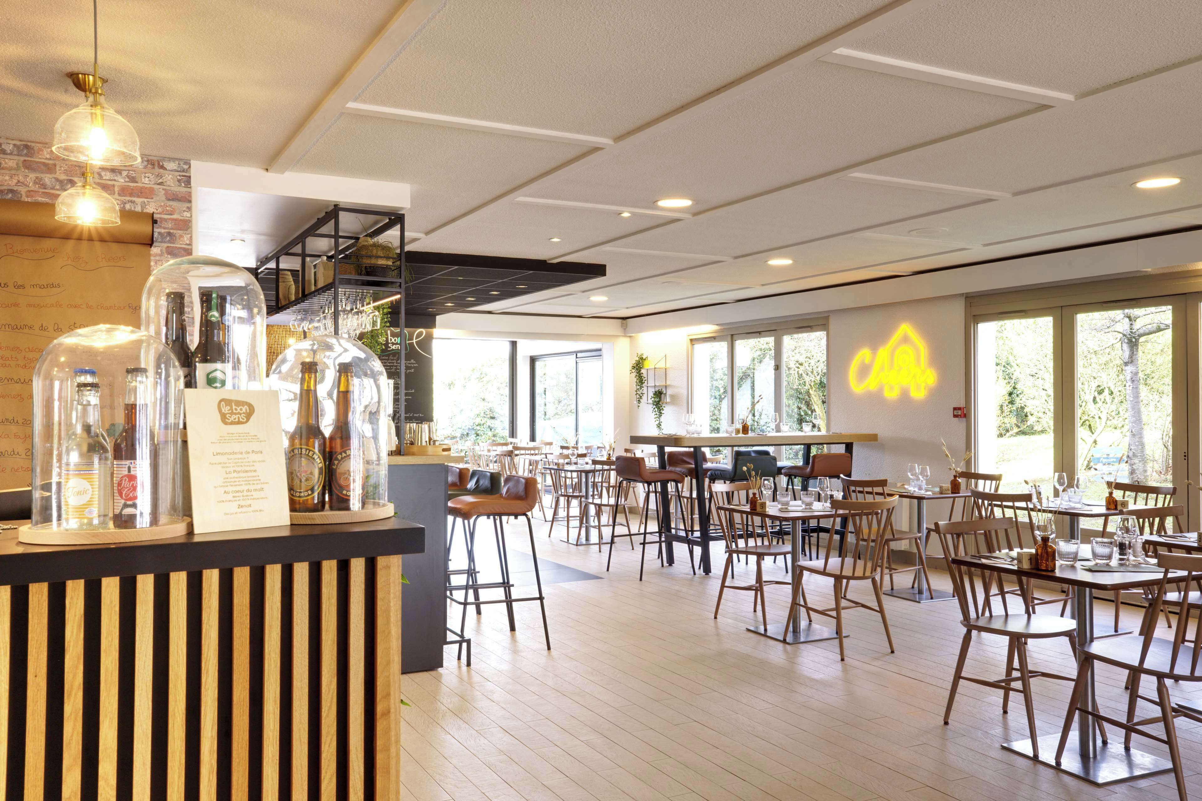 Un ristorante spazioso con pavimento in legno, numerosi tavoli e sedie, e ampie finestre che lasciano entrare luce naturale.