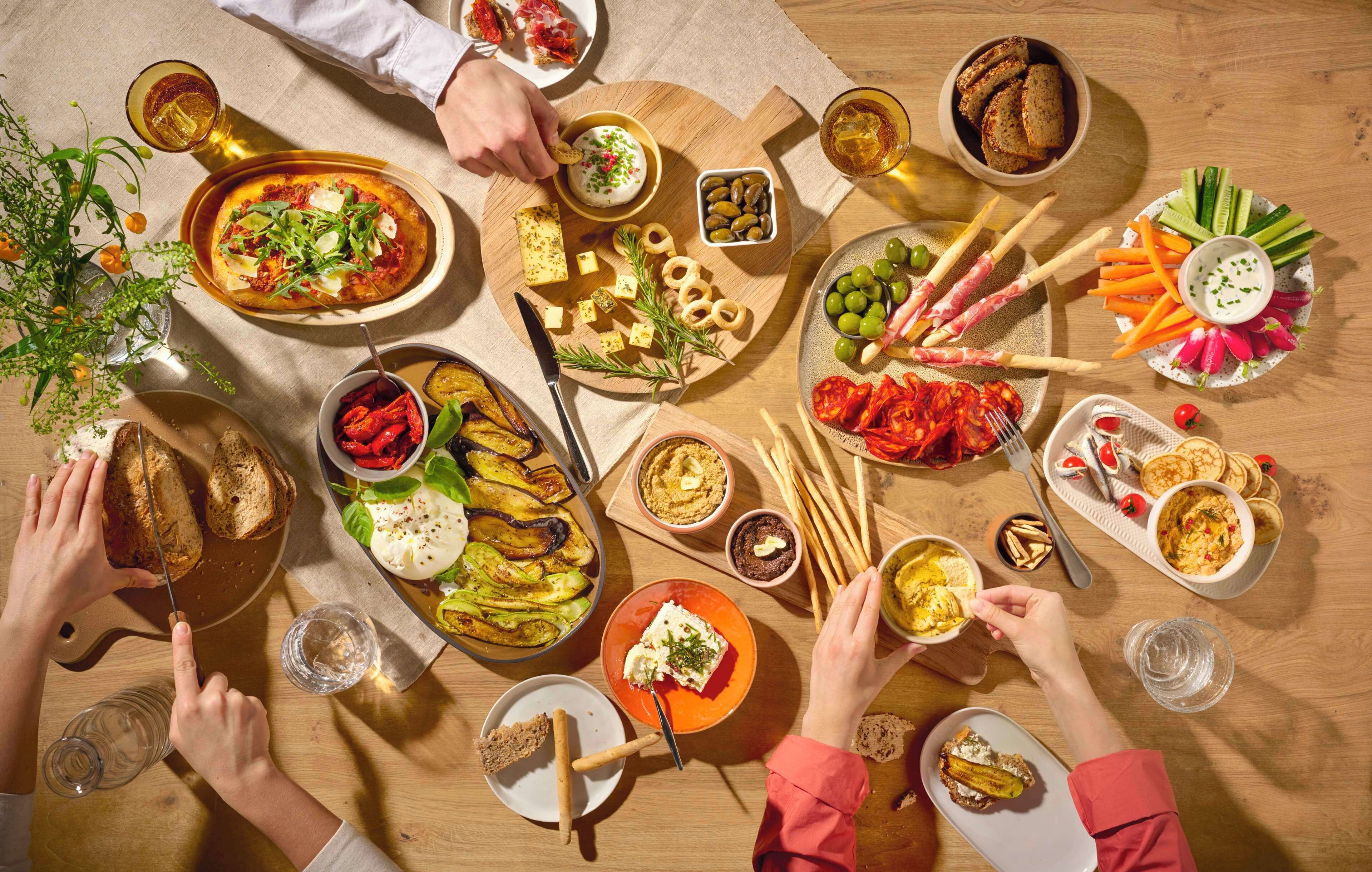 Una mesa con diversos alimentos y bebidas, como pan, queso y verduras.