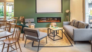 A modern living room with a fireplace, seating area, and a dining space. - Campanile Nature - Taverny (Taverny)