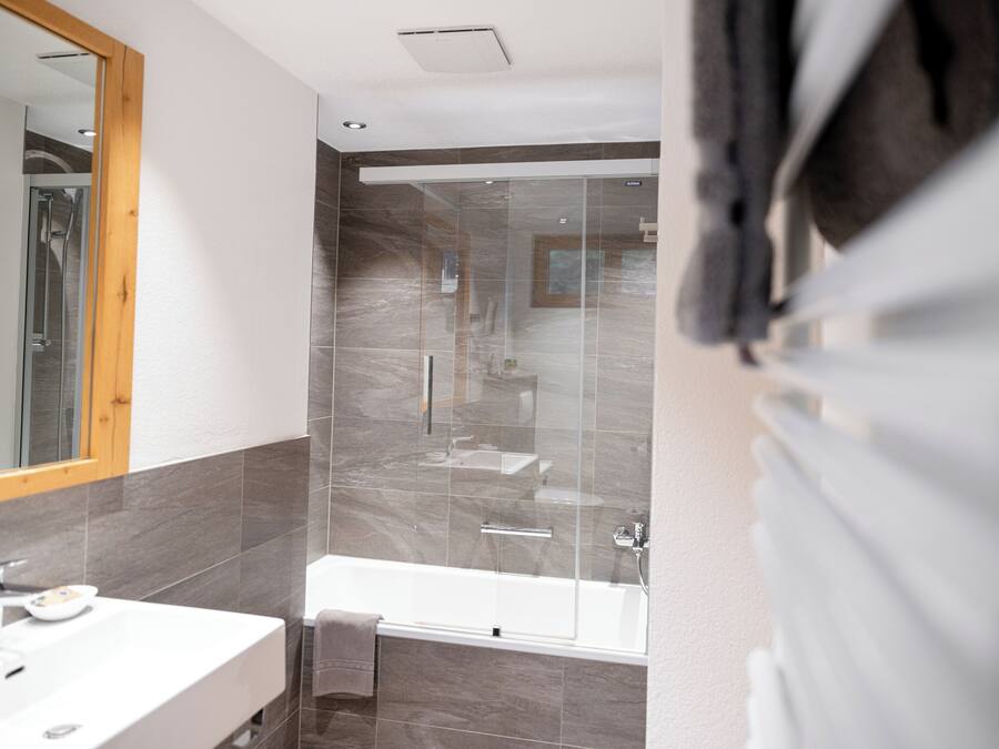 A modern bathroom with a glass shower enclosure, a bathtub, and a vanity with a mirror.