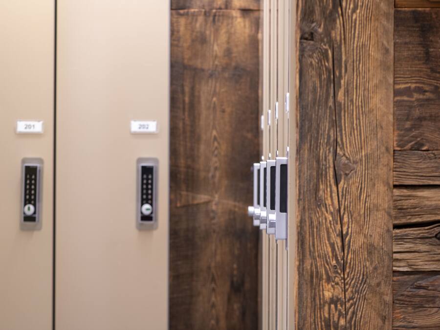 Two elevator doors with numbered panels, a wooden panel, and a metallic handle.