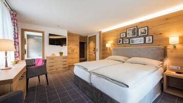 Ein modernes Schlafzimmer mit einem großen Bett, einem Holzschrank, einem Schreibtisch und einem Stuhl.