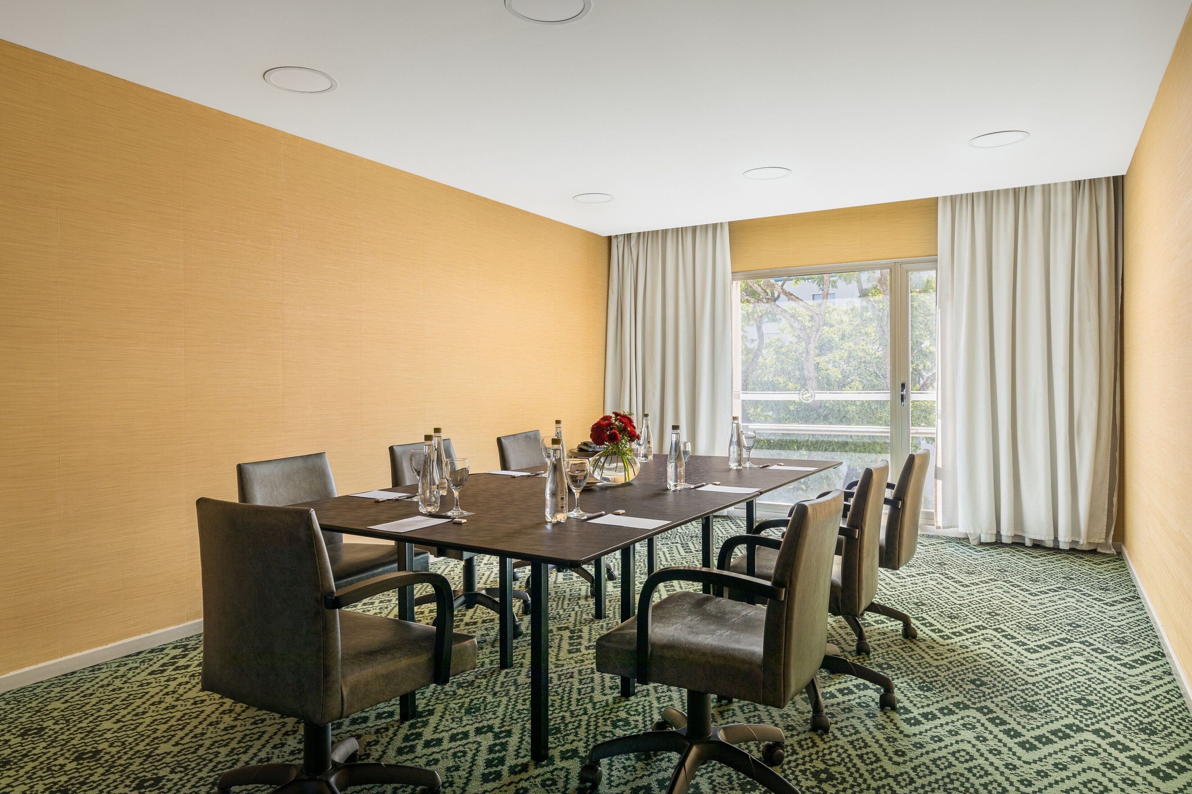 A conference room with a long table, chairs, and a vase with flowers.